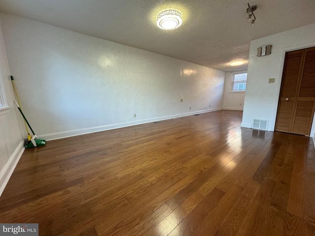 spare room featuring dark wood-type flooring and a textured ceiling