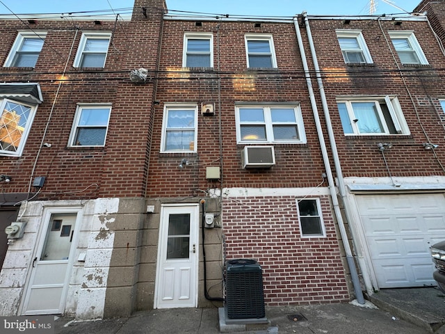 rear view of property featuring central AC unit and a garage