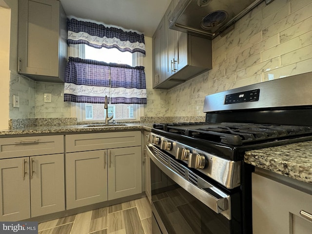 kitchen featuring gray cabinets, sink, light stone countertops, and stainless steel gas range