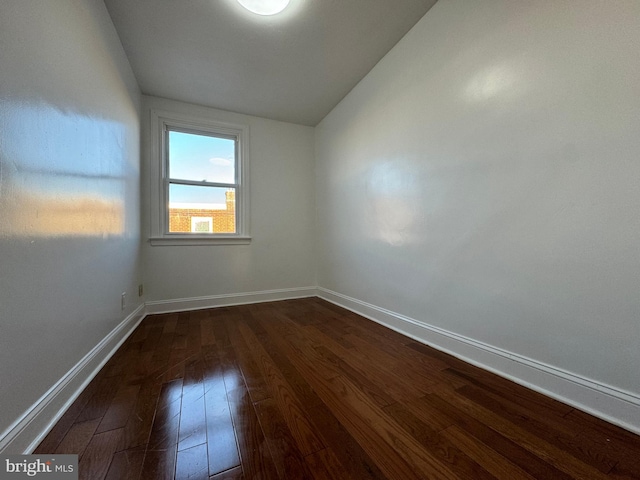 unfurnished room featuring dark hardwood / wood-style floors and vaulted ceiling