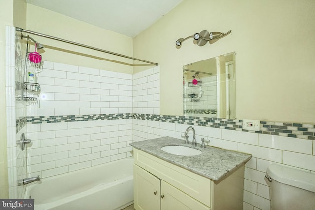 full bathroom with tile walls, vanity, toilet, and tiled shower / bath