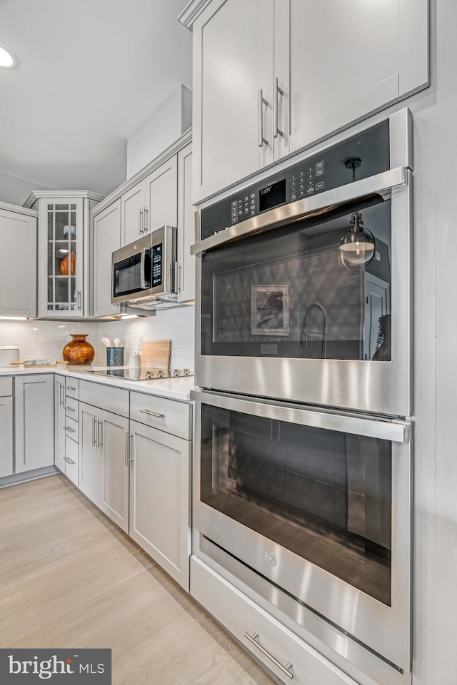 kitchen featuring decorative backsplash, light wood-type flooring, and appliances with stainless steel finishes