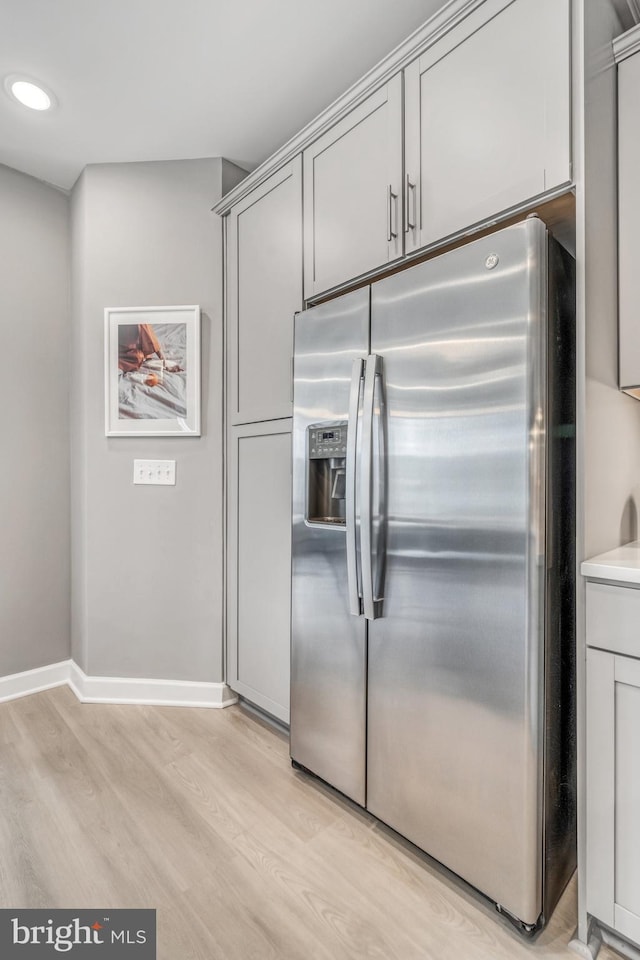 kitchen with gray cabinetry, stainless steel fridge with ice dispenser, and light hardwood / wood-style flooring