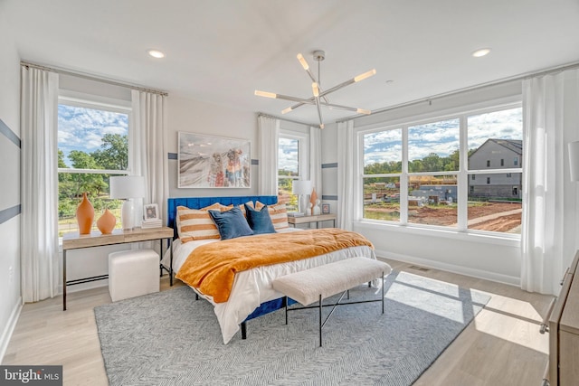 bedroom with light hardwood / wood-style floors and ceiling fan with notable chandelier