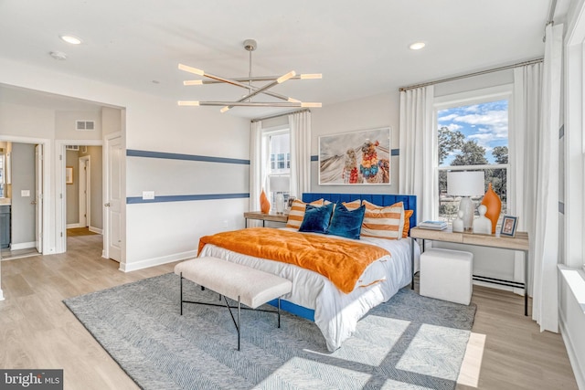 bedroom with light hardwood / wood-style flooring and a chandelier