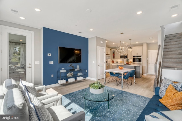 living room with a chandelier and light hardwood / wood-style floors