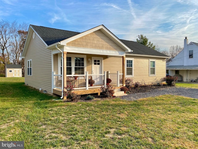 view of front facade with a front lawn, a shed, and covered porch