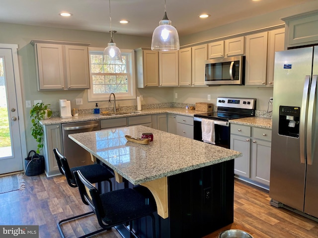 kitchen with stainless steel appliances, wood-type flooring, a center island, and plenty of natural light