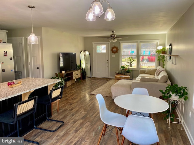 dining space with dark hardwood / wood-style flooring and ceiling fan with notable chandelier