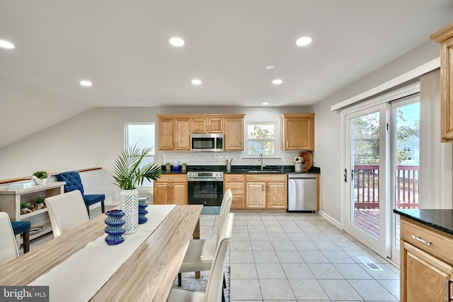 kitchen featuring light tile patterned flooring, stainless steel appliances, backsplash, sink, and lofted ceiling