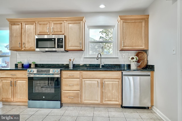 kitchen featuring dark stone counters, backsplash, appliances with stainless steel finishes, and sink