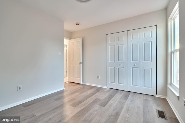 unfurnished bedroom with a closet and light wood-type flooring