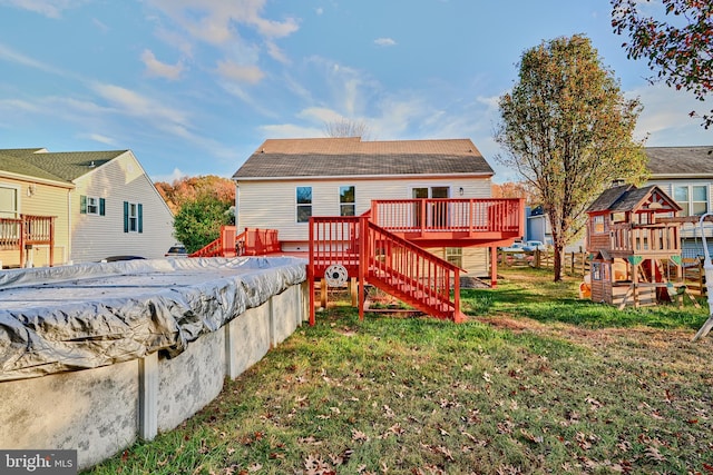 rear view of house featuring a lawn and a deck