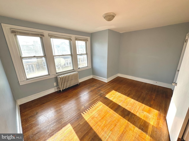 empty room with dark wood-type flooring and radiator