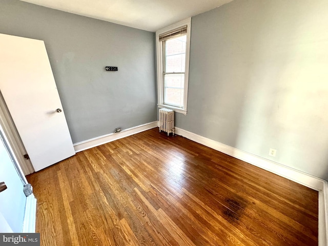 empty room featuring radiator heating unit and hardwood / wood-style flooring