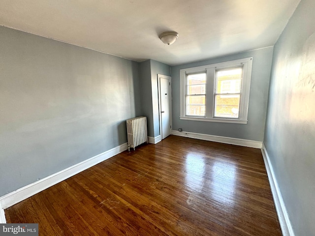 empty room with radiator and dark hardwood / wood-style flooring