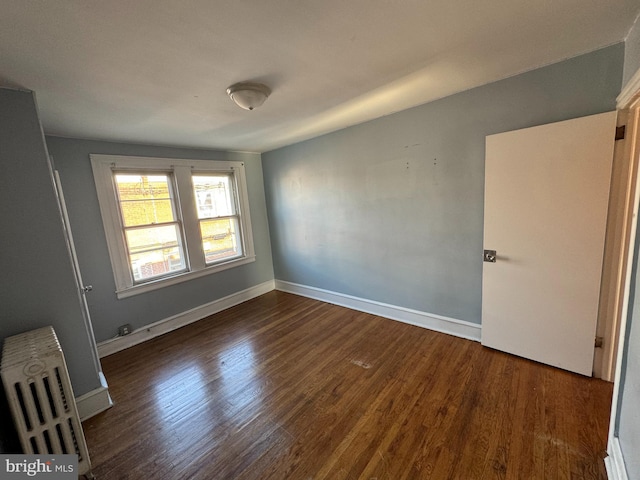 empty room with dark hardwood / wood-style floors and radiator