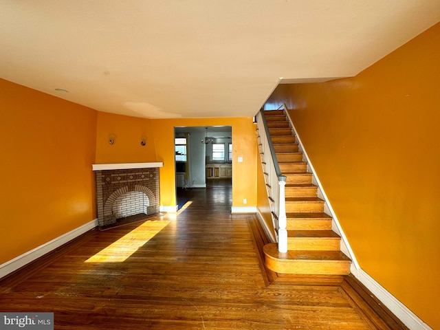 unfurnished living room with a brick fireplace and dark wood-type flooring