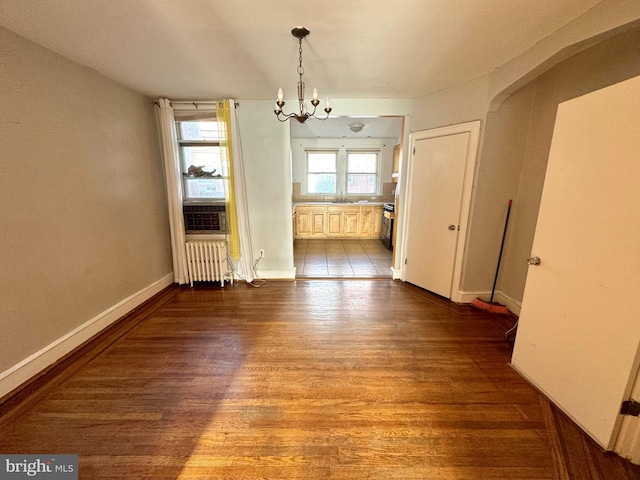 unfurnished dining area with sink, radiator heating unit, an inviting chandelier, and light hardwood / wood-style floors