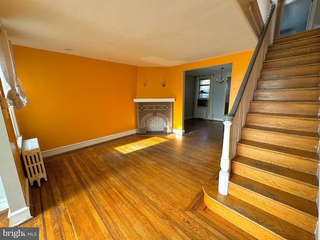 unfurnished living room featuring a brick fireplace and hardwood / wood-style floors