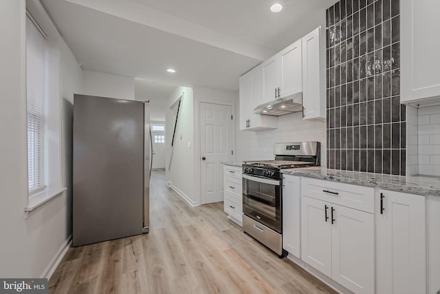 kitchen featuring light stone counters, white cabinets, gas stove, backsplash, and light wood-type flooring