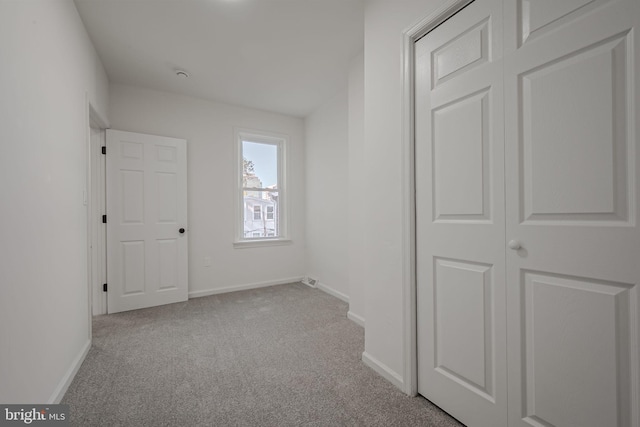 unfurnished bedroom featuring light carpet and a closet