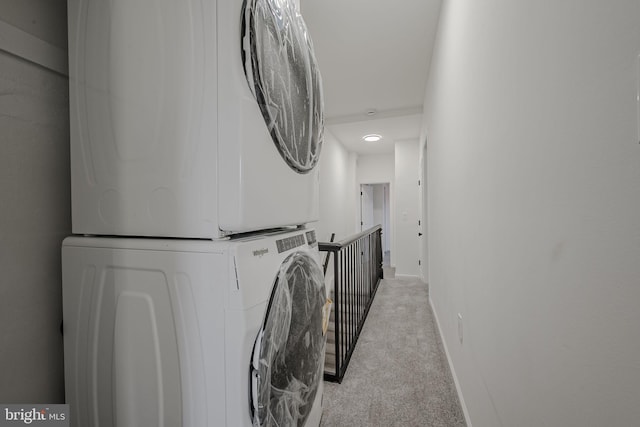 clothes washing area featuring stacked washing maching and dryer and light colored carpet