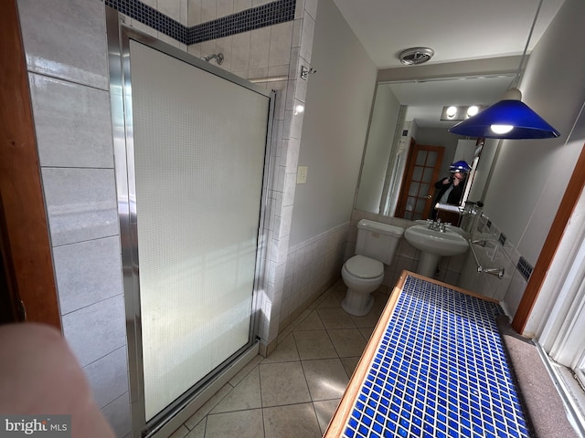 bathroom featuring walk in shower, tile patterned flooring, sink, toilet, and tile walls