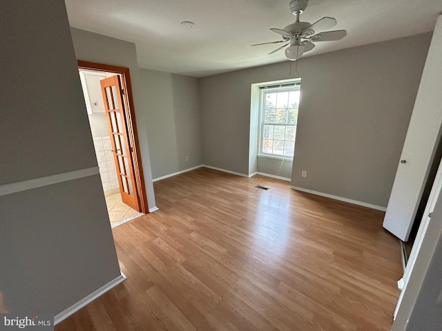 empty room with ceiling fan and light hardwood / wood-style flooring