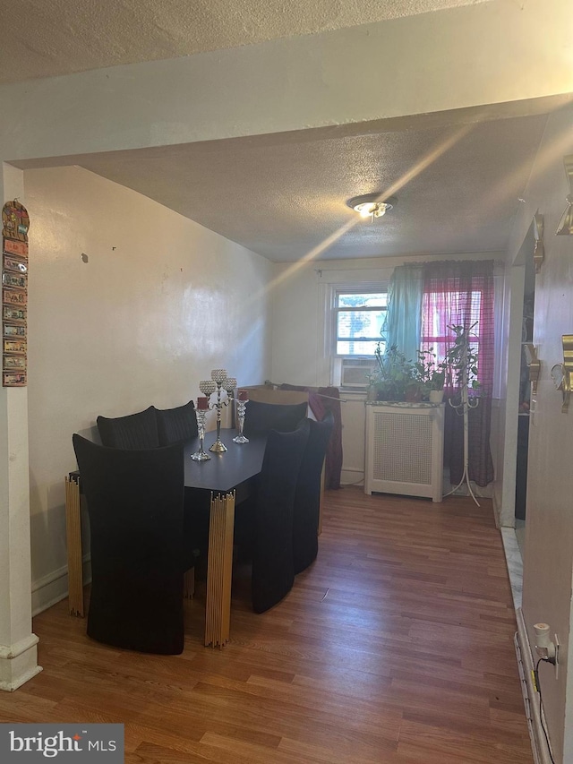 dining room featuring radiator, hardwood / wood-style floors, and a textured ceiling