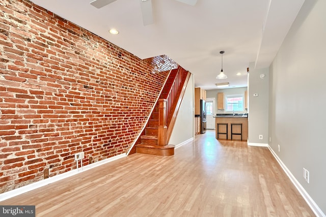 unfurnished living room featuring light hardwood / wood-style floors and brick wall