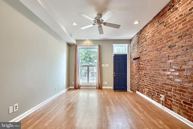 spare room featuring ceiling fan, brick wall, and light hardwood / wood-style flooring