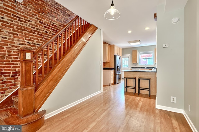 stairs featuring hardwood / wood-style flooring, brick wall, and sink