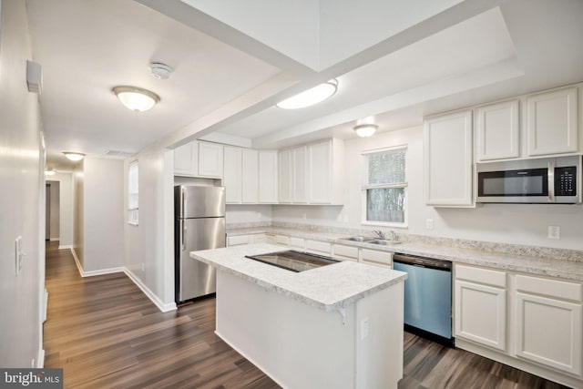 kitchen with appliances with stainless steel finishes, dark hardwood / wood-style flooring, sink, white cabinets, and a center island