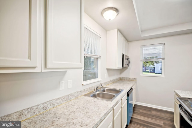 kitchen with white cabinets, sink, dark hardwood / wood-style floors, light stone countertops, and appliances with stainless steel finishes