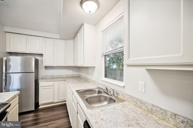 kitchen with light stone countertops, appliances with stainless steel finishes, dark wood-type flooring, sink, and white cabinets