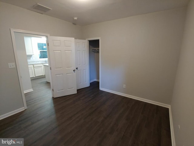 unfurnished bedroom with a closet and dark wood-type flooring