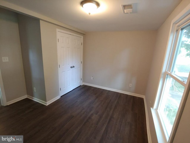 unfurnished bedroom featuring a closet and dark hardwood / wood-style floors