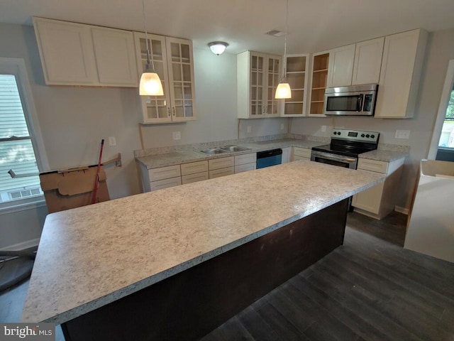 kitchen featuring sink, dark wood-type flooring, stainless steel appliances, pendant lighting, and white cabinets