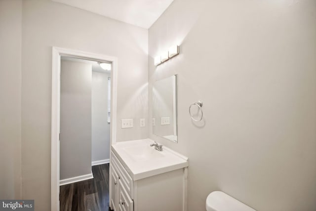 bathroom with hardwood / wood-style floors, vanity, and toilet