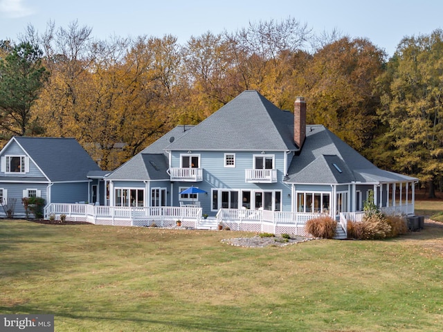 rear view of property featuring a balcony, central AC unit, and a lawn