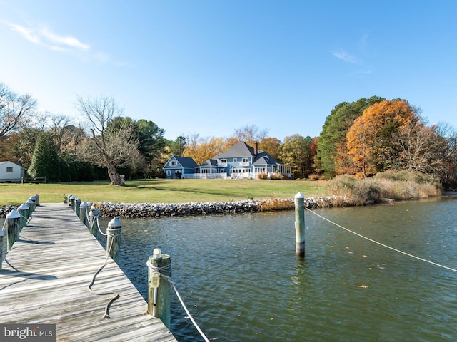 view of dock with a lawn and a water view