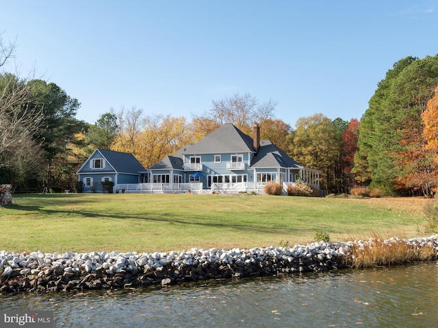 rear view of property with a lawn and a water view