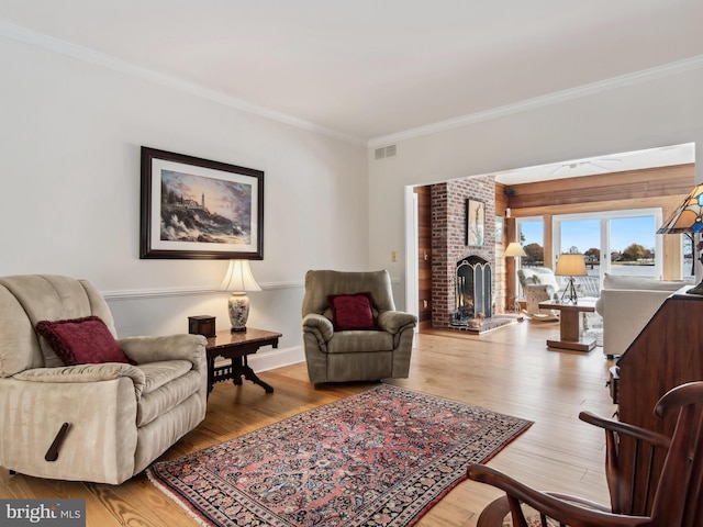 living room with a brick fireplace, light hardwood / wood-style flooring, and ornamental molding