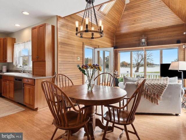 dining room featuring wood walls, light hardwood / wood-style floors, a notable chandelier, and sink