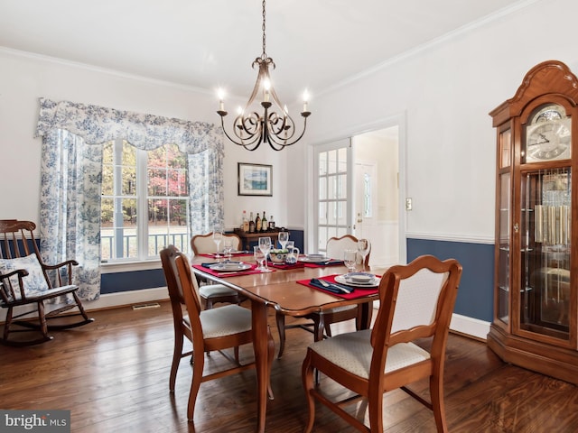 dining space with dark hardwood / wood-style flooring, crown molding, and a chandelier