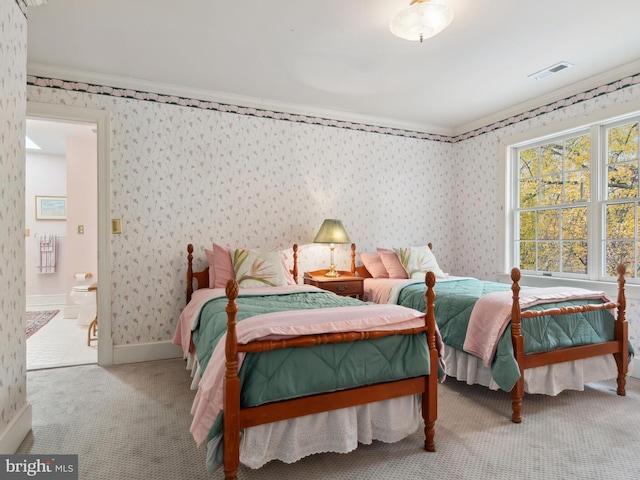 carpeted bedroom with crown molding and ensuite bath