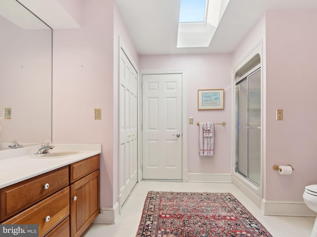 bathroom with vanity, toilet, a shower with door, and a skylight