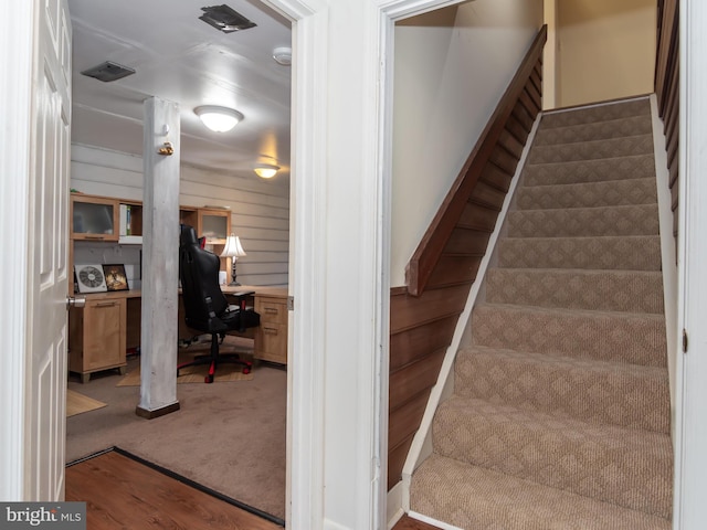 staircase with wooden walls and carpet floors