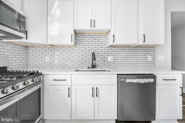 kitchen featuring stainless steel appliances, white cabinetry, sink, and backsplash